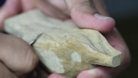 Man-carving-wood-to-create-a-bird-figurine