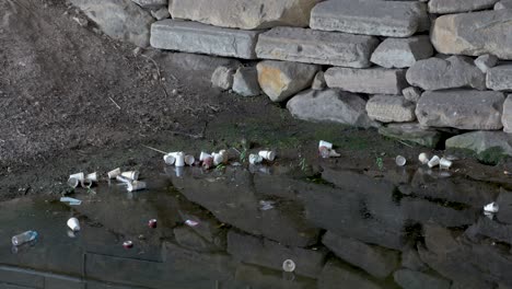 Polystyrene-Cup-Floats-in-Polluted-Water-with-Plastic-Bottles,-Cans-and-Waste