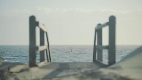 Red-buoy-float-floating-in-rough-sea-with-staircase-down-to-the-beach