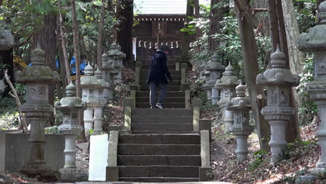 A-adult-man-calls-with-his-arm-to-climb-up-the-old-stairs-at-of-a-Japaneses-shrine