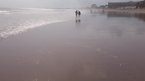 Silhouette-Von-Zwei-Menschen,-Die-Am-Strand-In-Bali,-Seminyak,-Indonesien,-Spazieren-Gehen