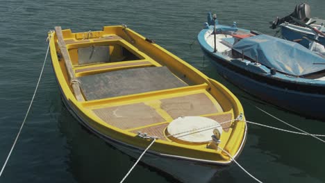 Small-bright-yellow-plastic-lake-boat-moored-at-seaside-harbor-plywood-panels-slow-motion