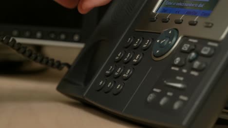 A-close-up-of-a-hand-picking-up-and-dialing-an-office-phone-then-hanging-up