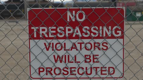 A-quick-zoom-in-on-a-red-and-white-no-trespassing-sign-that-is-behind-a-chain-linked-fence