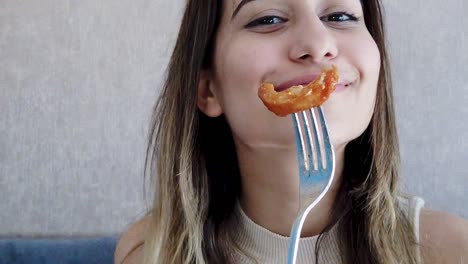 Slow-motion:Beautiful-young-girl-shows-chicken-piece-food-on-fork-with-a-big-enjoy-in-a-restaurant-or-cafe-while-sitting