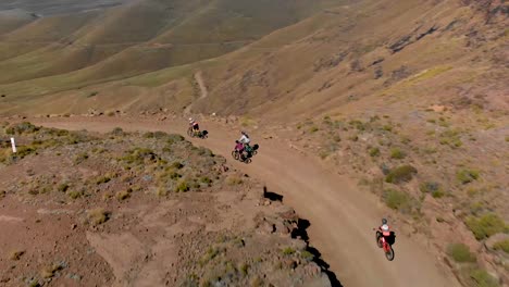 Aerial-view-following-mountain-bikers-going-down-a-mountain-pass-60fps