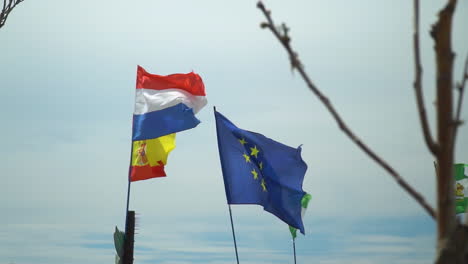 Flag-of-EU,-France,-Spain-and-Andalucia-waving-in-slow-motion-in-front-of-pale-blue-sky