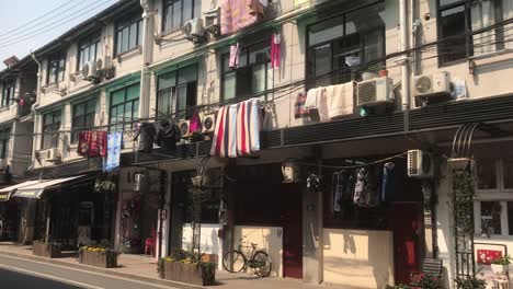 hand-held-shot-of-an-urban-genuine-musty-backyard-area-in-French-Concession,-Shanghai-on-a-cold-sunny-blue-sky-day-with-laundry-hanging-on-the-balconies