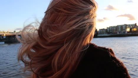 Woman's-Hair-blowing-around-on-Riverbank-at-Sunset