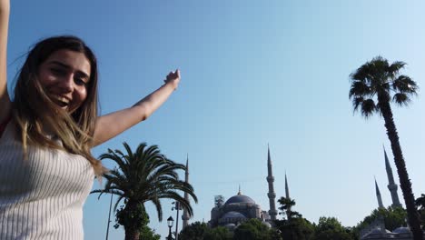 Slow-motion:Beautiful-young-girl-waves-Turkish-flag-with-view-of-Sultan-Ahmed-or-Blue-mosque-in-İstanbul,Turkey,Travel-concept