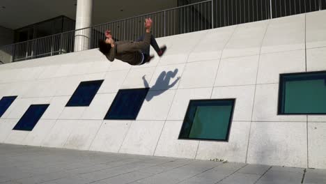 Young-parkour-athlete-doing-a-wall-backflip-of-a-modern-building-in-4k