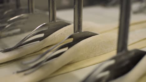 folding-raw-pastry-dough-automatically-by-industrial-automated-machine-inside-a-bread-factory