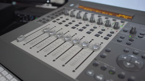 Dolly-above-looking-down-on-audio-mixer-as-dials-move-on-their-own
