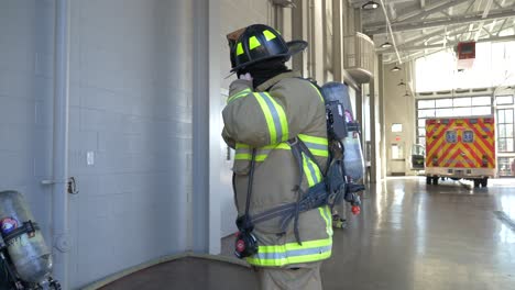 Firefighter-puts-on-firefighting-gear-with-air-tank-and-helmet-to-be-ready-to-fight-a-fire