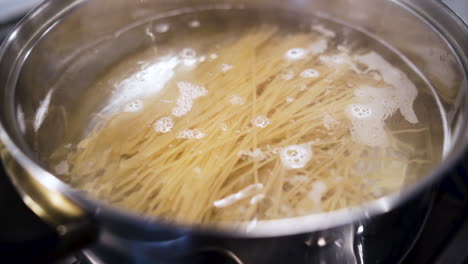 Wir-Lassen-Eine-Handvoll-Spaghetti-Nudeln-In-Zeitlupe-In-Einen-Topf-Mit-Kochendem-Wasser-Fallen