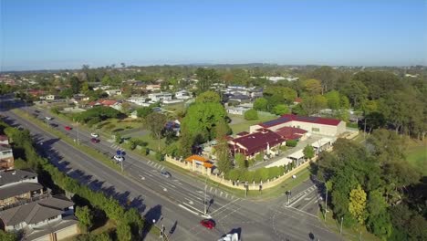 Beautiful-aerial-drone-shot-with-a-smooth,-wide-orbit-of-a-Vietnamese-temple-in-suburban-Brisbane,-as-the-drone-pulls-back-to-reveal-a-busy-intersection