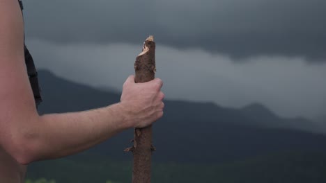Hikers-Hand-With-Walking-Stick-Watching-Over-Mountains-as-Rain-Storm-Approaches-Close-Up
