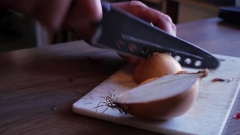 Close-Up-Handheld-Shot-of-an-Old-Man-Cutting-Some-Onions-on-a-White-Cutting-Board-With-a-Sharp-Knife-and-Picks-Them-Up-for-a-Cajun-Dish
