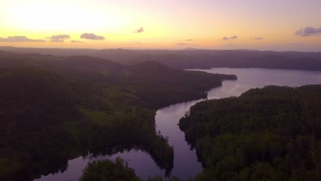 Aerial-view-of-a-river-through-tropical-forest-valley-at-sunset