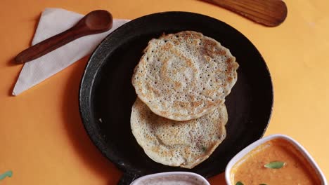 Rotating-Oothappam---Dosa---South-Indian-breakfast-using-rice-lentil-and-vegetables-served-with-coconut-chutneyisolated-on-yellow-background