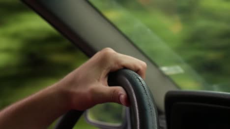 CLose-Up-shot-of-a-hand-tightly-gripping-the-steering-wheel-of-a-car-while-driving