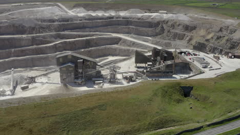 An-aerial-view-of-a-working-asphalt-quarry-building-with-the-quarry-cut-in-the-background,-Yorkshire,-UK