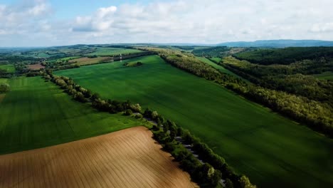 Aerial-landscape-slideling-shot-of-cloudy-bright-and-shady-view-of-agricultural-areas-hills-and-little-forest-summer-zala-county-hungary-europe