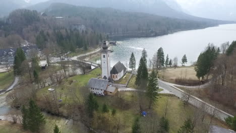 Drone-Subiendo-Por-Encima-Del-Puente-Y-La-Iglesia-Del-Lago-Bohinj,-Eslovenia