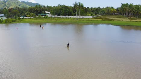 Aerial-view-across-group-of-men-adjusting-nets-in-tropical-lagoon-water
