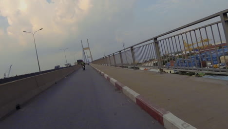 1-of-3-parts-of-crossing-the-Phu-My-Bridge-on-Motorcyle-showing-the-approach,-structure-of-the-bridge,-other-vehicles-and-shipping-on-the-river-below