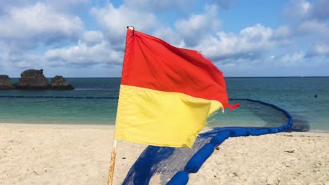 Tattered-Red-and-Yellow-Surf-Life-Saving-Flag-Blowing-In-The-Wind