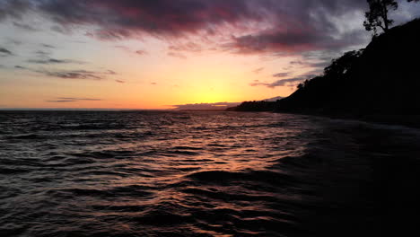 Tief-über-Den-Meereswellen-Fliegen-Mit-Farbenfrohen-Sonnenuntergangsreflexionen-Am-Strand-In-Santa-Barbara,-Kalifornien.-Luftdrohne