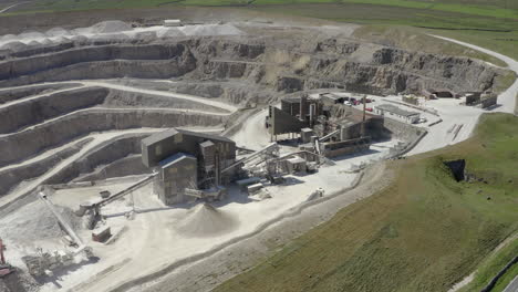 An-aerial-view-of-a-working-asphalt-quarry-building-with-the-quarry-cut-in-the-background,-Yorkshire,-UK