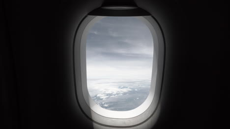 4K-Clip-Eines-Flugzeugfensters,-Aufgenommen-Aus-Der-Kabine-Während-Einer-Reise-Und-Eines-Fluges-An-Einem-Stürmischen-Tag-Mit-Dunklen,-Unheimlichen-Wolken-Am-Himmel