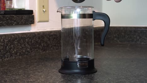 Scooping-coffee-grounds-into-a-french-press-coffee-maker