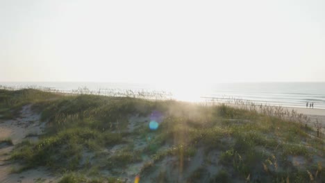 4k-view-of-beach-access-rising-over-the-dunes-to-reveal-the-ocean-at-sunrise-with-lens-flare