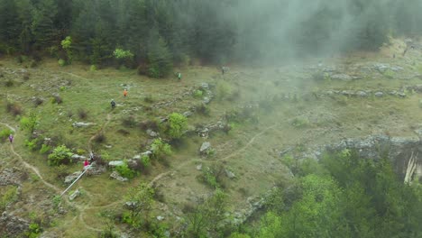 Aerial-Pan,-Marathon-runners-jog-in-foggy-Bulgarian-forest-hillside