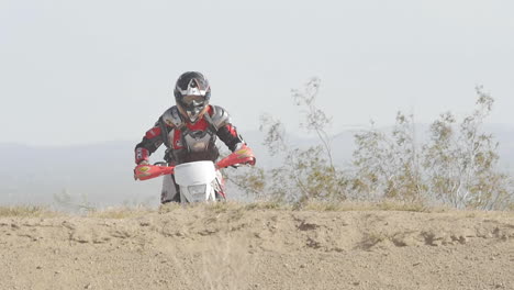 Zeitlupe:-Ein-Dirtbiker-Springt-Mit-Seinem-Roten-Motorrad-Von-Einer-Anhöhe-In-Der-Wüste
