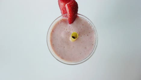 Healthy-smoothie-prepared-by-blender-served-on-the-white-background-and-decorated-with-srawberry-and-the-yellow-straw