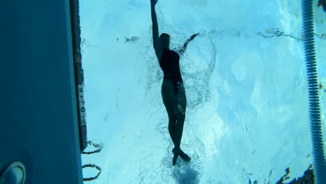 Underwater-shot-of-a-female-swimming-through-the-lane-of-a-pool-using-perfect-form