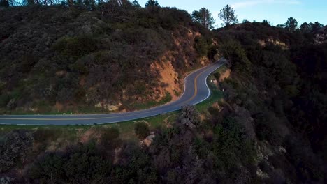 Tight-Curve-of-Mountain-Road-beside-Steep-Cliff-at-Dawn,-Drone-Slide-L