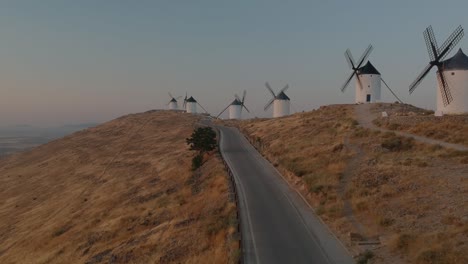Aerial-shot-over-a-road-near-a-row-of-windmills-in-Consuegra,-Spain