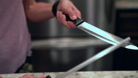 Closeup-of-woman-sharpening-knife-in-slow-motion-with-light-bouncing-off-the-blade