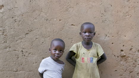 Two-boys-standing-in-front-of-wall-in-Slum-neighborhood-outside-of-Kigali,-Rwanda