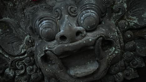 Slow-Motion-hand-held-shot-slowly-rotating-towards-an-ancient-monkey-statue-at-the-Sacred-Monkey-Forest-in-Bali,-Indonesia