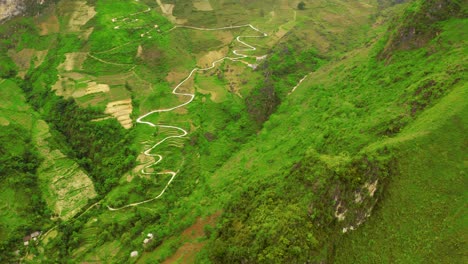 Aerial-ascending-shot-over-a-mountain-revealing-a-winding-road-cut-into-the-mountains-of-the-gorgeous-Ma-Pi-Leng-Pass-in-northern-Vietnam