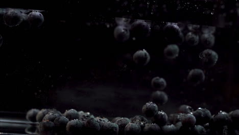 Slow-Motion-Of-Blueberries-Floating-Into-Water-Against-Black-Background