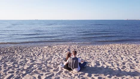 Aerial-Shot-Of-Young-Couple-Sitting-On-Sandy-Beach,-Hugging