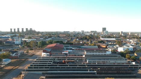 A-panning-right-drone-shot-of-Industry-buildings-in-the-outskirts-of-Bulawayo,-Zimbabwe-at-sunset