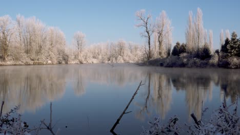 Slow-tracking-wide-shot-of-a-calm-river-lined-with-snow-covered-trees